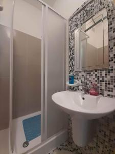 MġarrEast Breeze Penthouse的浴室配有盥洗盆和带镜子的淋浴