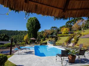 蒙特韦尔迪Pousada Varanda das Colinas的度假村的游泳池,带椅子和树木