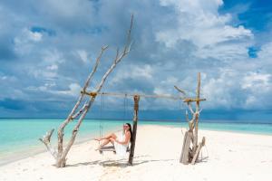 OmadhooTurtle Maldives - Your Gateway to the Beach & Marine Adventures Await!的坐在海滩秋千上的女人