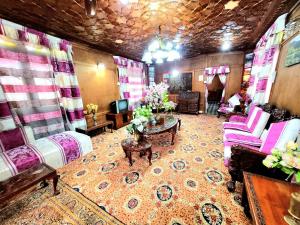 斯利那加Aziz Palace Group Of Houseboats的客厅配有粉红色的椅子和桌子