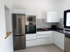 蒂纳霍Apartamentos Falcón的厨房配有白色橱柜和不锈钢冰箱