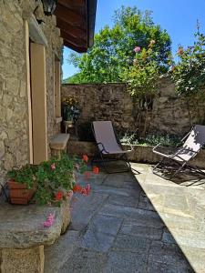 阿尔梅诺Casa Elisa affittacamere的一座建筑前的庭院,庭院内摆放着两把草坪椅和鲜花