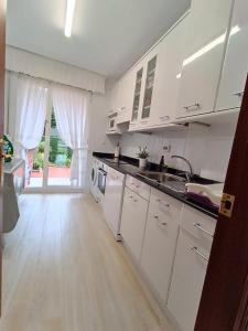 MiengoApartamento con jardin privado junto playa Usil - Mogro的厨房铺有木地板,配有白色橱柜。