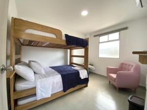 圣贝尔纳多德尔比恩托NAHIR apartamento de playa en condominio Palmar del viento的卧室配有两张双层床和一张粉红色的椅子。