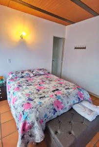 瓜塔佩Descanso Bajo La Piedra Del Peñol的卧室内的一张带花卉棉被的床
