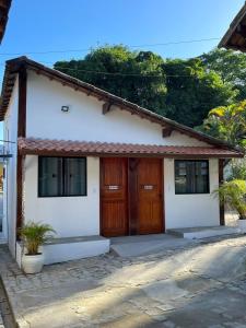 卡舒埃拉斯迪马卡库Pousada Rosa dos Ventos Kchu的白色的小房子,木门和窗户