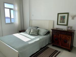 瓜拉派瑞Apartamento vista do mar, pé na areia e águas tranquilas, no cento de Guarapari的一间卧室配有一张带木床头柜和窗户的床。