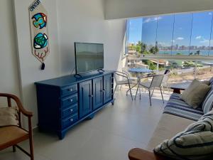 瓜拉派瑞Apartamento vista do mar, pé na areia e águas tranquilas, no cento de Guarapari的客厅配有蓝色梳妆台和电视机