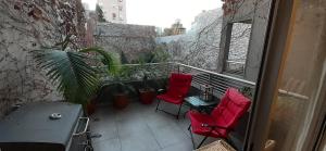 布宜诺斯艾利斯CONFORT BELGRANO的阳台配有2把红色椅子和桌子