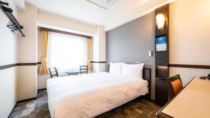 富山东横INN-富山站新干线出口2的酒店客房设有床和窗户。