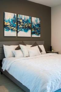 迈阿密Luxury Oceanview Studio at Miami Design District的卧室配有一张白色床,墙上挂有四幅画作