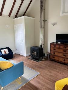 布莱尔高里Blairbeg Cottage的客厅配有蓝色的沙发和炉灶。
