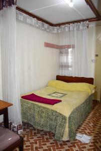 纳库鲁Sundowner Lodge的配有窗帘的窗户的客房内的一张床位