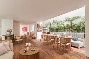 胡志明市Silverland Mây Hotel的客厅配有桌椅,棕榈树