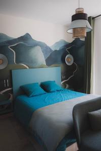 Salles-sur-MerLogis de l'Héronière的卧室配有一张蓝色的床,墙上挂着一幅画