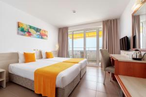 奥布佐尔AluaSun Helios Beach - All Inclusive的酒店客房配有一张床、一张书桌和一台电视。