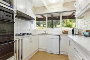 吉斯伯恩Gisborne Peak Winery Short Term Stays的厨房配有白色橱柜和炉灶烤箱。