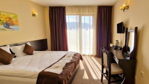 多布里尼什特Семеен хотел Света Марина的酒店客房配有一张床、一张书桌和一台电视。