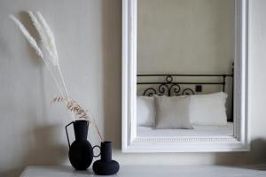 阿吉奥斯伊欧尼斯阿加皮托斯别墅宾馆的镜子和两个花瓶放在一个桌子上