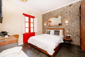 维多利亚Battistini Boutique Living Hotel and Spa, Victoria, Gozo的一间卧室设有一张大床和一扇红色的门