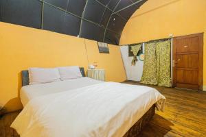 JunggoChikar Glamping At Wisata Coban Talun Mitra RedDoorz的卧室设有一张白色大床和一扇窗户。