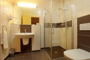 诺伊鲁平诺伊鲁平运动酒店的一间带玻璃淋浴和水槽的浴室