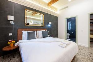 维多利亚Battistini Boutique Living Hotel and Spa, Victoria, Gozo的卧室配有一张大床,墙上装有镜子