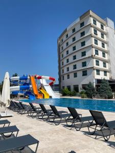 YeniköyThe Sign Kocaeli Thermal Spa Hotel &Convention Center的一个带滑梯和椅子的游泳池以及一个水滑梯