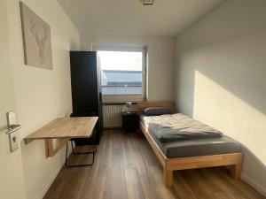 汉堡"Live Good, Work Good" - Stadion Apartment by GG Rental Hamburg的一间卧室配有一张床、一张桌子和一个窗户。