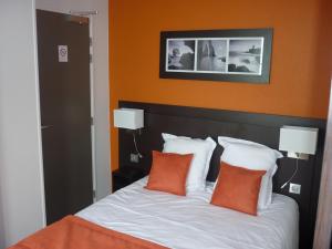 基贝维尔Hotel De La Plage的一张带橙色墙壁的床和两个枕头