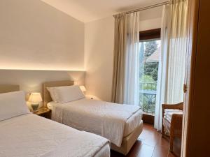 加尔达湖滨Villa Phoenix - Lake Apartments的酒店客房设有两张床和窗户。
