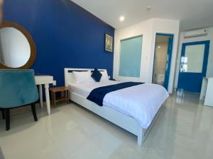 绥和市Alicia Hotel的蓝色卧室配有一张大床和一张书桌