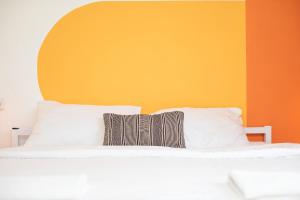 耶鲁姆The White Hill Guesthouse的一张带白色枕头和橙色墙壁的床