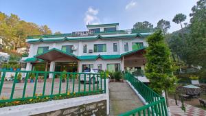 卡绍利Pineland Resorts & Chalets Kasauli的前面有绿色围栏的房子