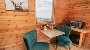 斯卡伯勒Shepherds Hut by Stepney Stays的一间带桌椅和窗户的用餐室