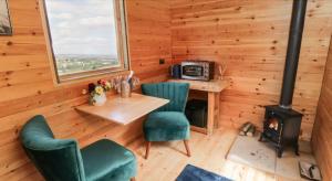 斯卡伯勒Shepherds Hut by Stepney Stays的客房设有桌椅和炉灶。
