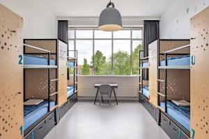 阿姆斯特丹Stayokay Hostel Amsterdam Oost的客房设有双层床、桌子和窗户。