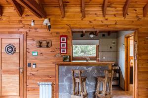 拉安戈斯图拉镇BOG Melania - casa en el bosque的一间带木墙的厨房和一间带凳子的酒吧