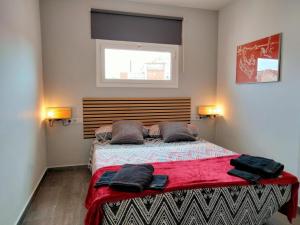 巴塞罗那Apartamentos Turísticos Tenor by Bossh Hotels的一间卧室配有一张带红色床单的床和一扇窗户。