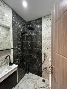 乌宗Netya Suite Hotel的浴室铺有黑白瓷砖,设有淋浴。
