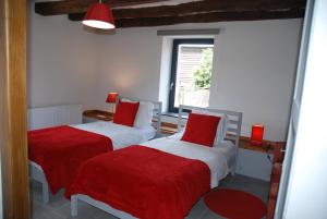 DohanB&B Le Courtil的一间卧室设有两张带红色床单的床和窗户。