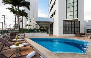 纳塔尔Plaza Suítes Natal的一座带躺椅的游泳池和一座建筑