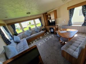 惠特利湾Let's Caravan at Whitley Bay的客厅配有沙发和桌子