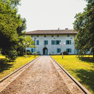 Villa Trigatti Udine Galleriano的前面有一条土路的大建筑