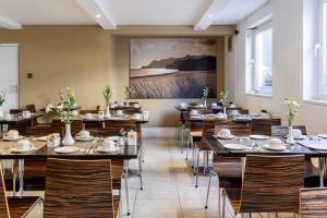 伦敦肯辛顿苑酒店 - 伯爵府 的餐厅设有桌椅,墙上挂有绘画作品