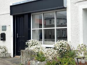 圣贾斯特Charming Studio in Heart of Vibrant St Just, West Cornwall的白色花房的黑色门