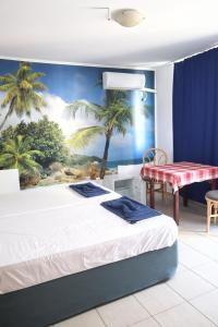 阳光海滩Къща за гости "Arawana"的一间卧室配有床和棕榈树壁画