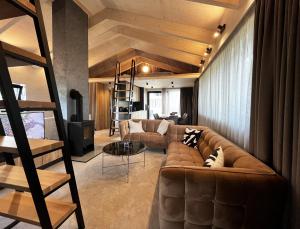 鲁容贝罗克Rezidencia Hrabovo的一间带棕色真皮沙发的客厅和一个阁楼