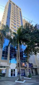 新伊瓜苏梦布隆钻石公寓式酒店的一座高大的建筑,前面有棕榈树