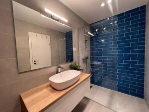 伯德古拉Beachfront Comfort Apartments SINAJKO的浴室设有水槽、镜子和蓝色瓷砖